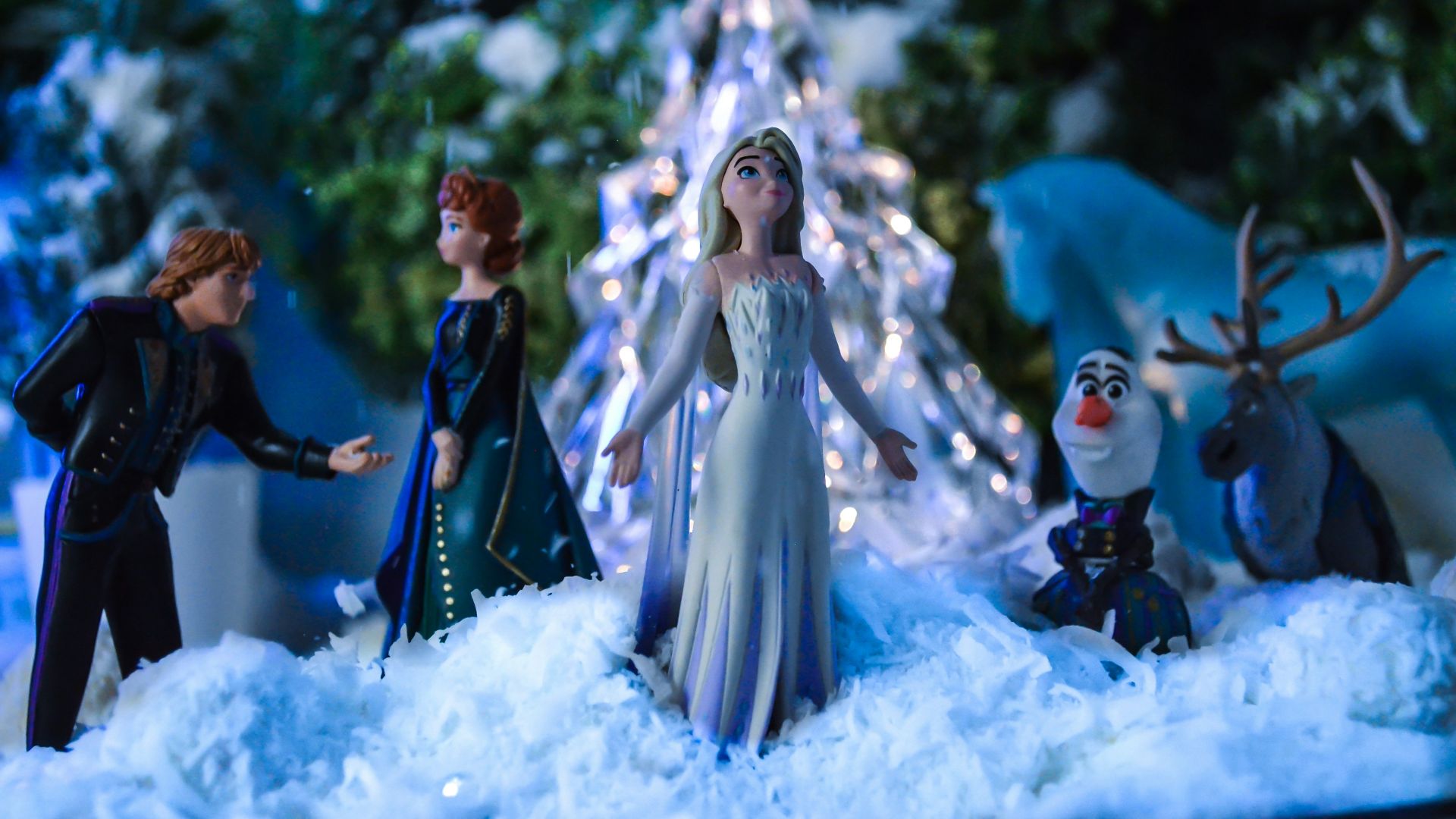 a group of figurines standing in front of a christmas tree