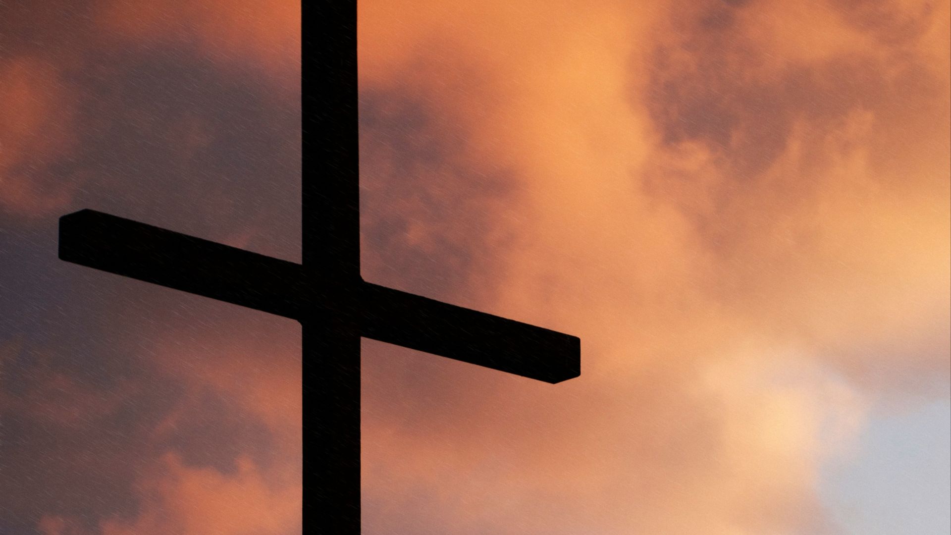 silhouette of large cross under orange sky
