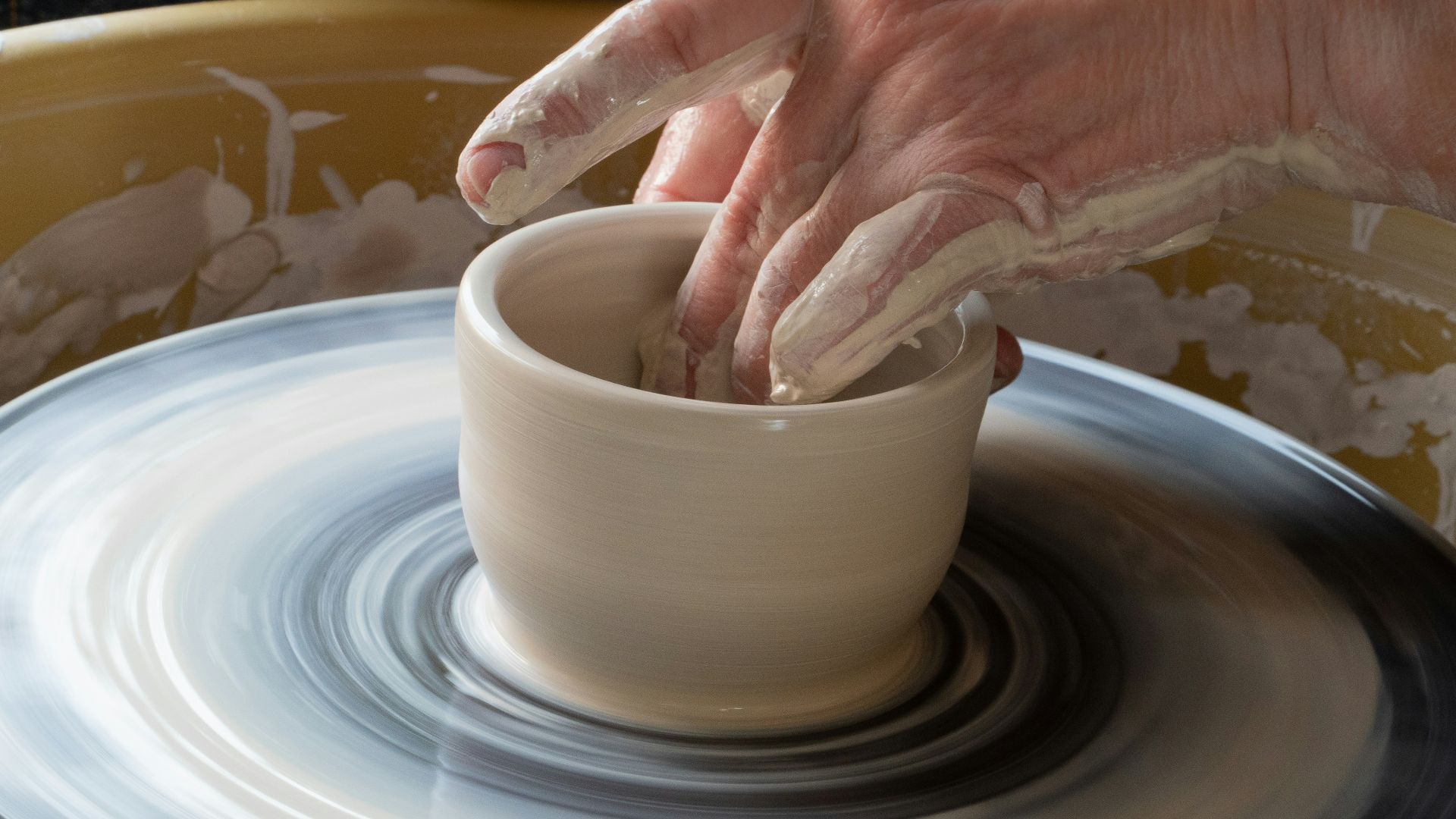 person making clay pot on white round plate
