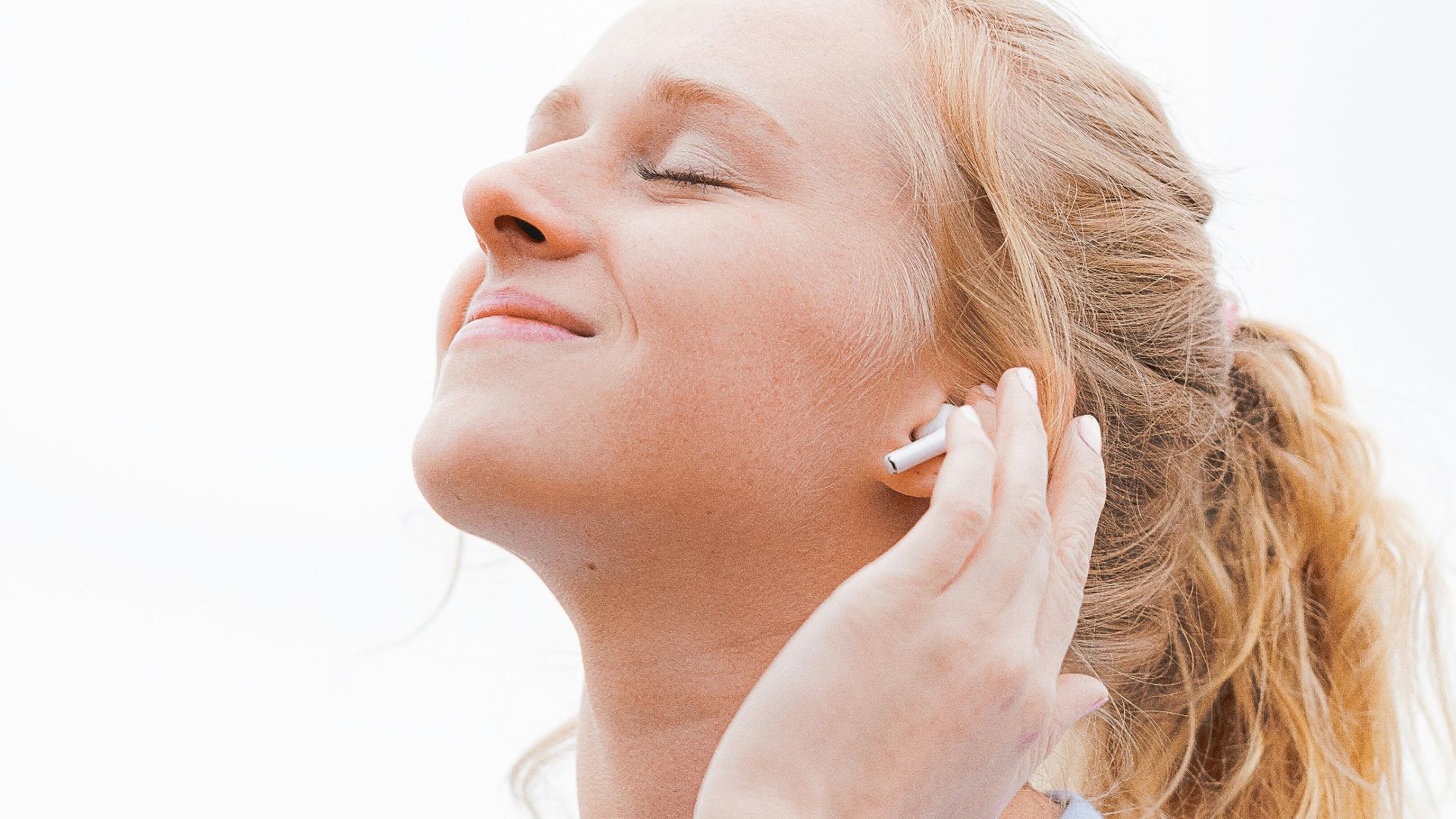 woman in white crew neck shirt covering her face with her hand