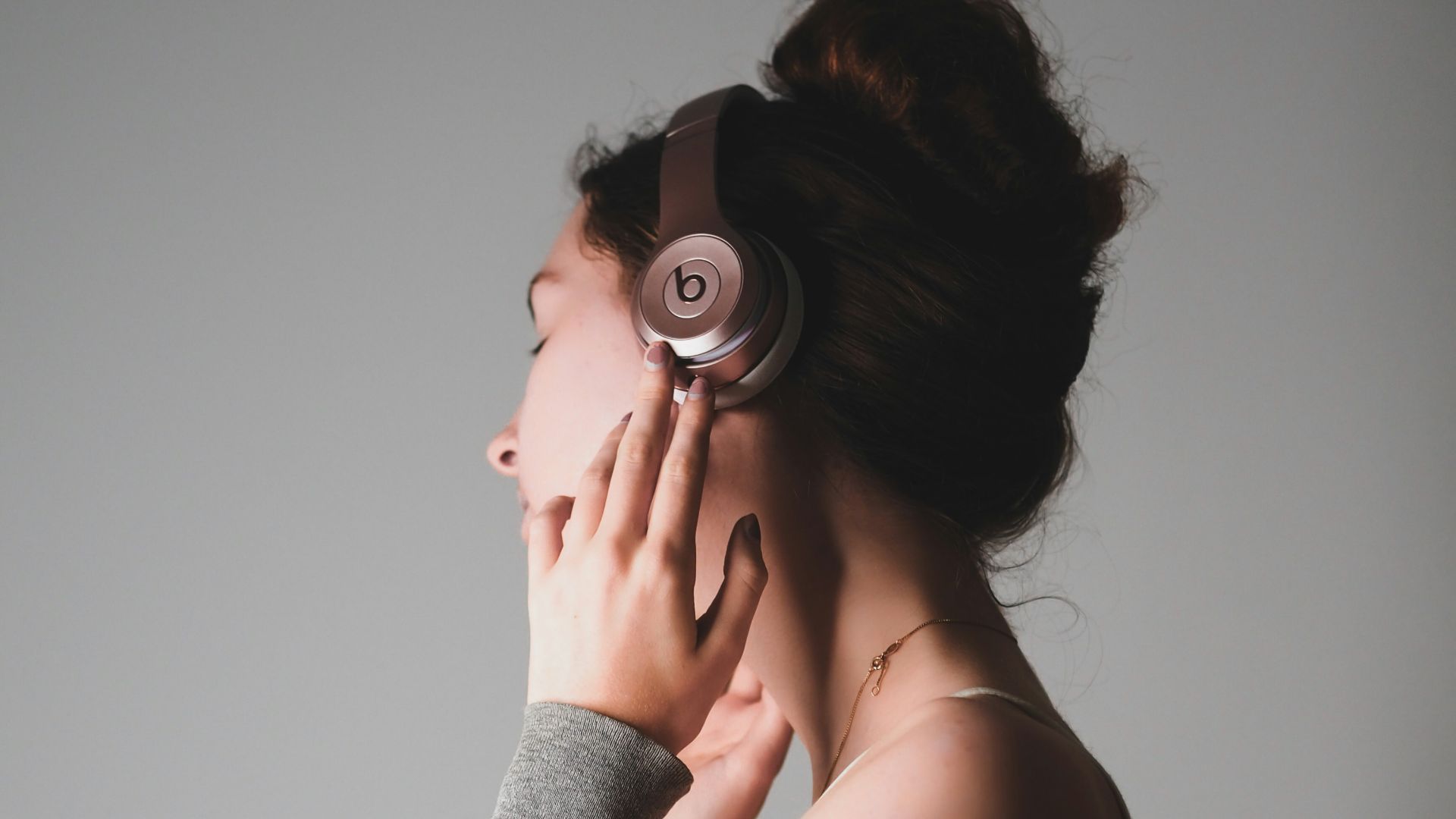 woman in gray long sleeve shirt covering her face with her hands