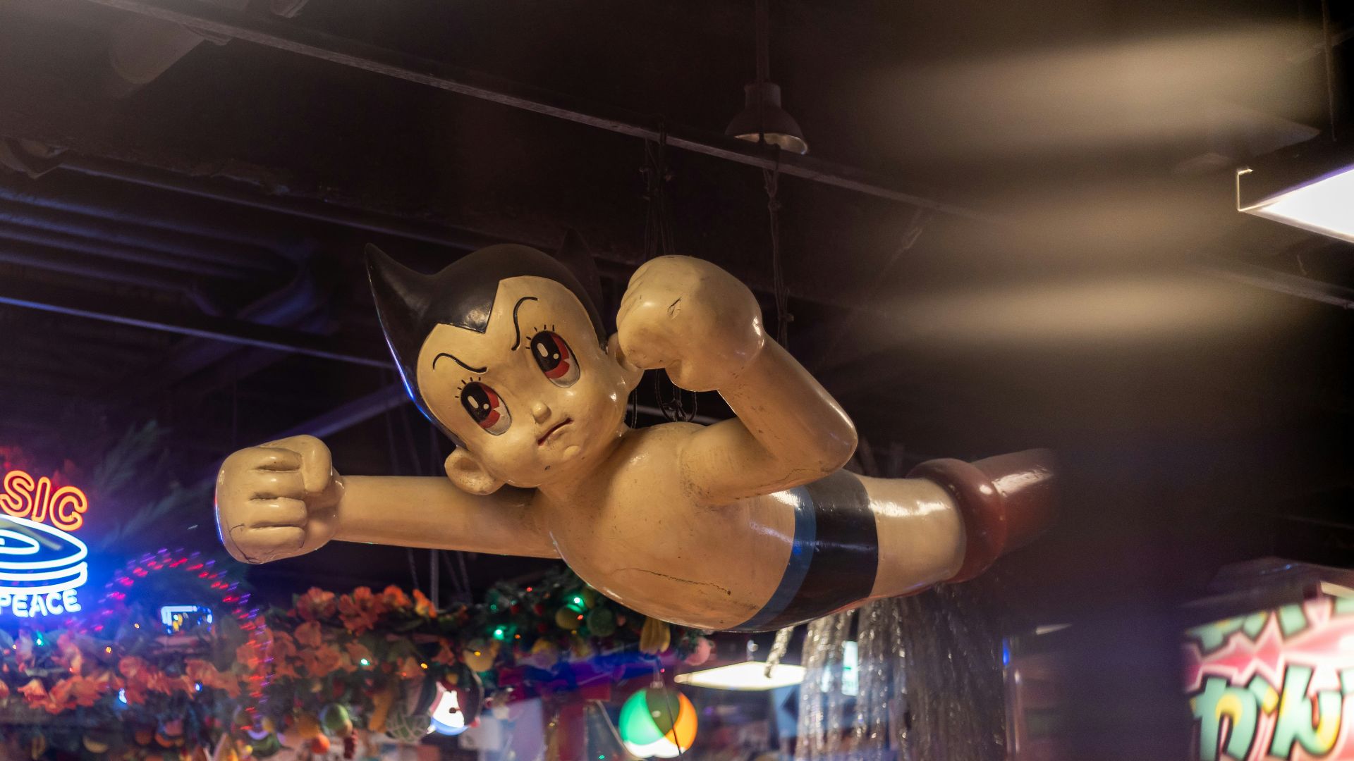 Astro boy flies over a busy arcade.