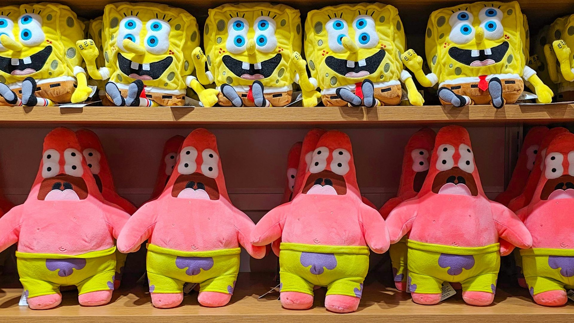 A shelf filled with lots of yellow and pink stuffed animals
