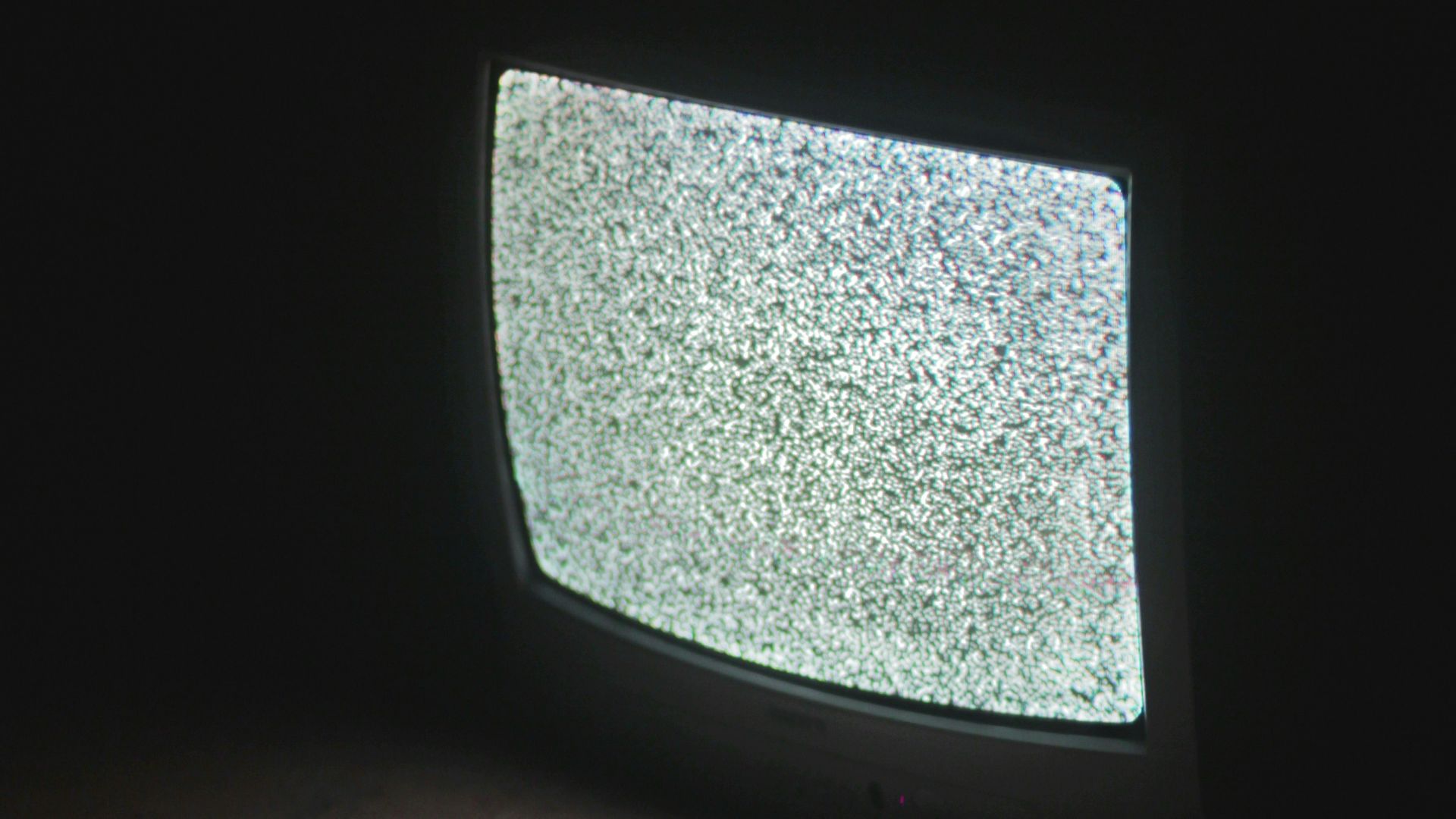 gray crt tv turned on in a dark room