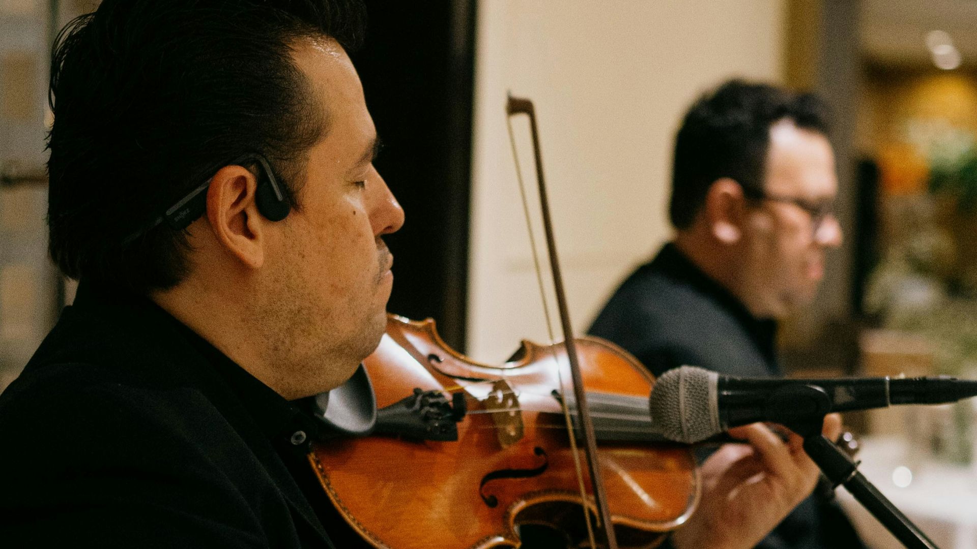 Musicians playing violins in a formal setting.