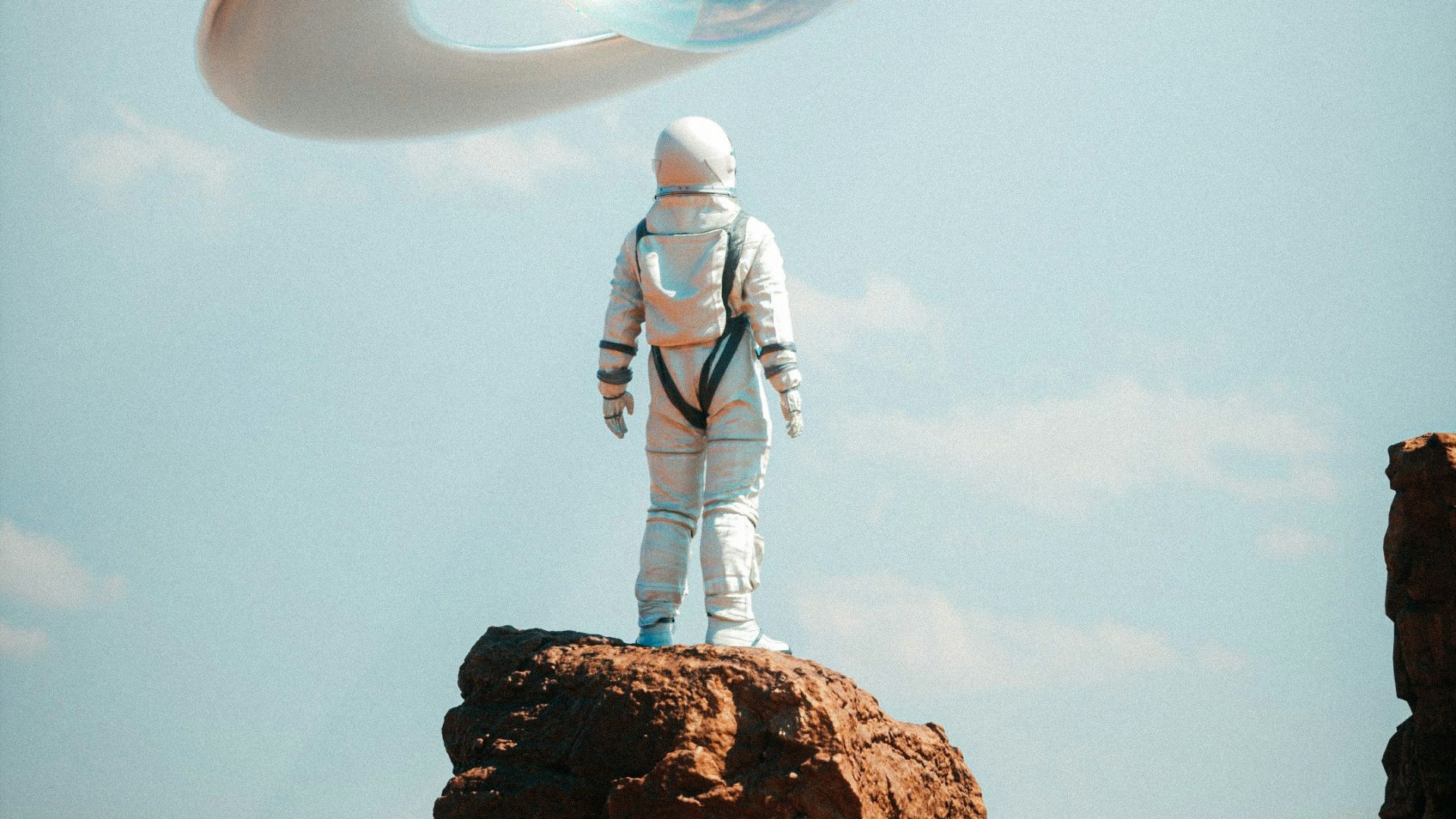 a man in a space suit standing on top of a rock