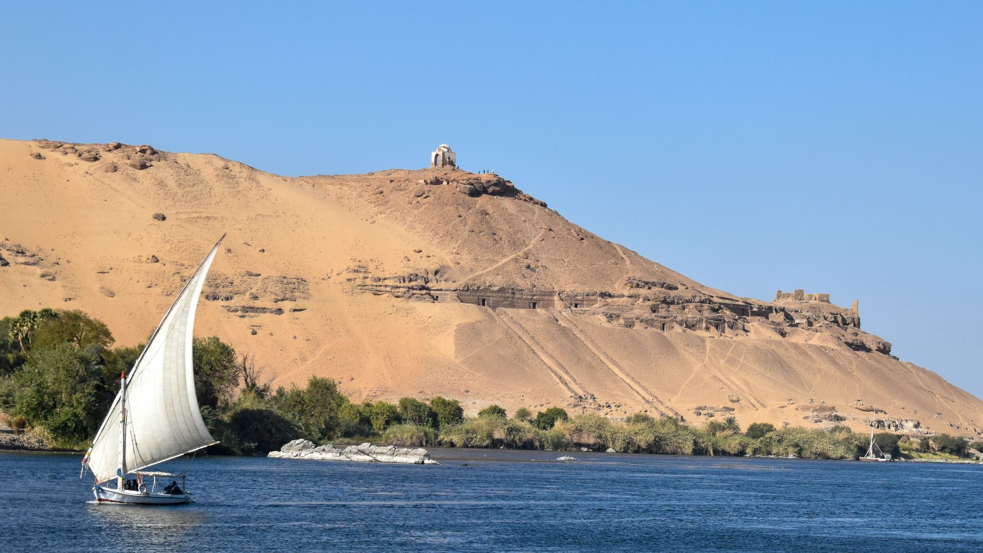 a sailboat in a body of water with a mountain in the background