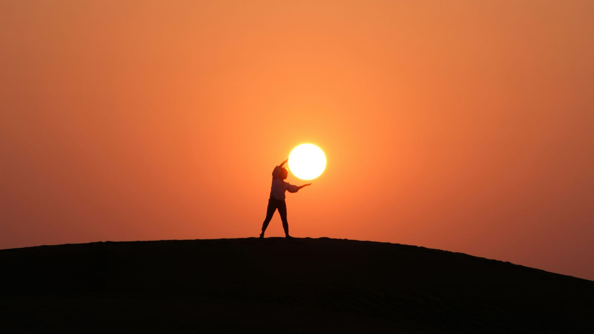 silhouette of person standing on hill during sunset