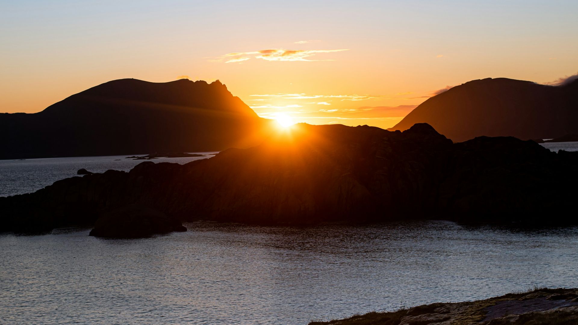 blue and red tent on brown rock near body of water during sunset