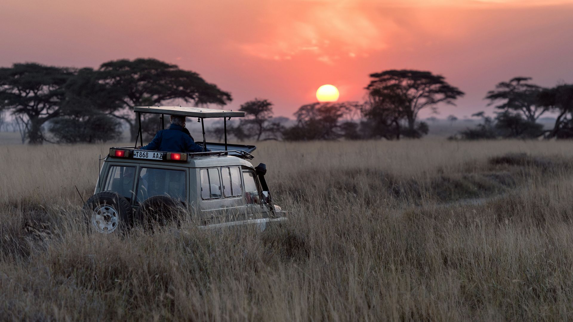 man riding on gray car during sunset