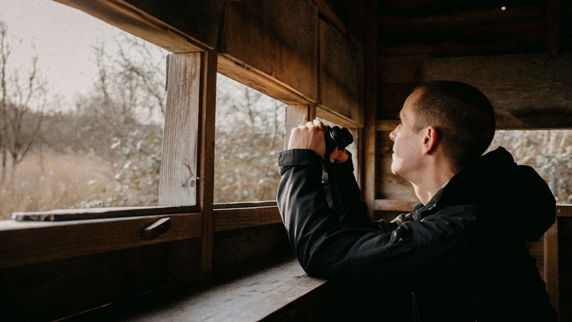 a man looking out of a window in a cabin