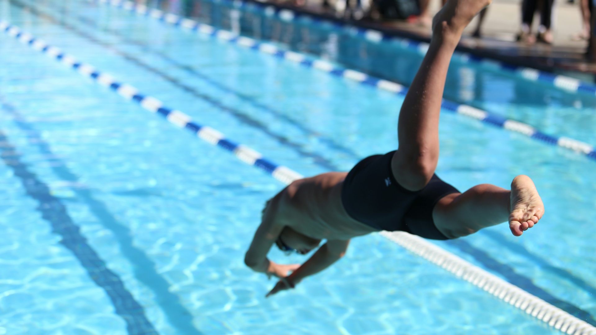 woman in black one piece swimsuit jumping on swimming pool during daytime