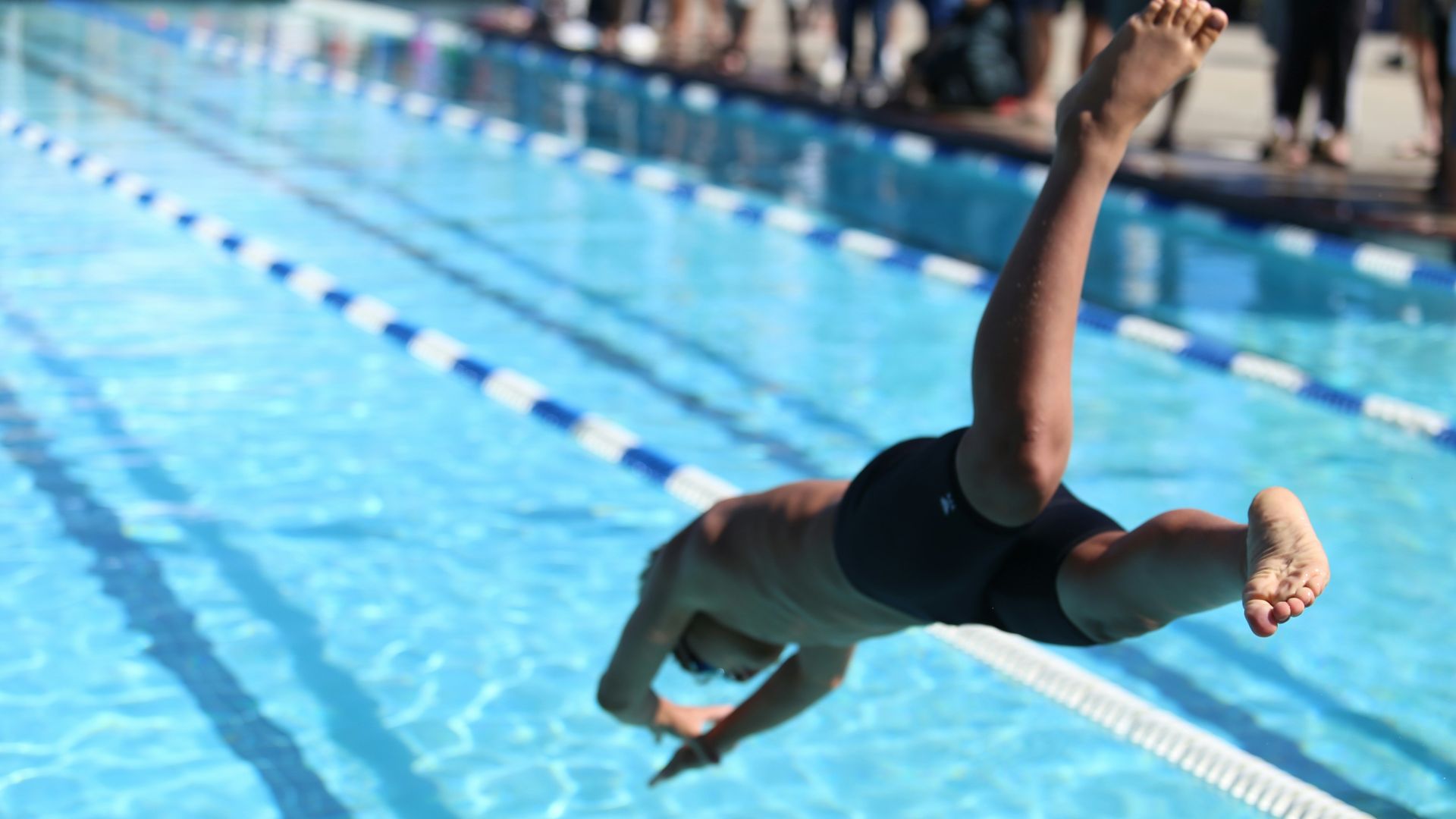 woman in black one piece swimsuit jumping on swimming pool during daytime