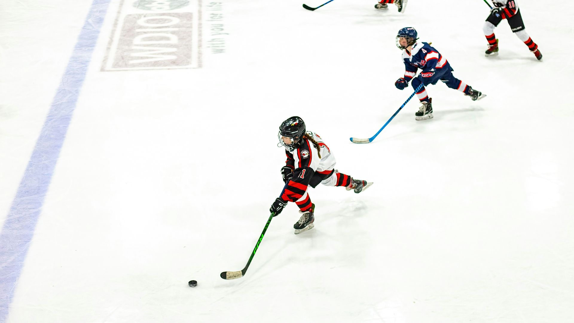 a group of young children playing a game of ice hockey