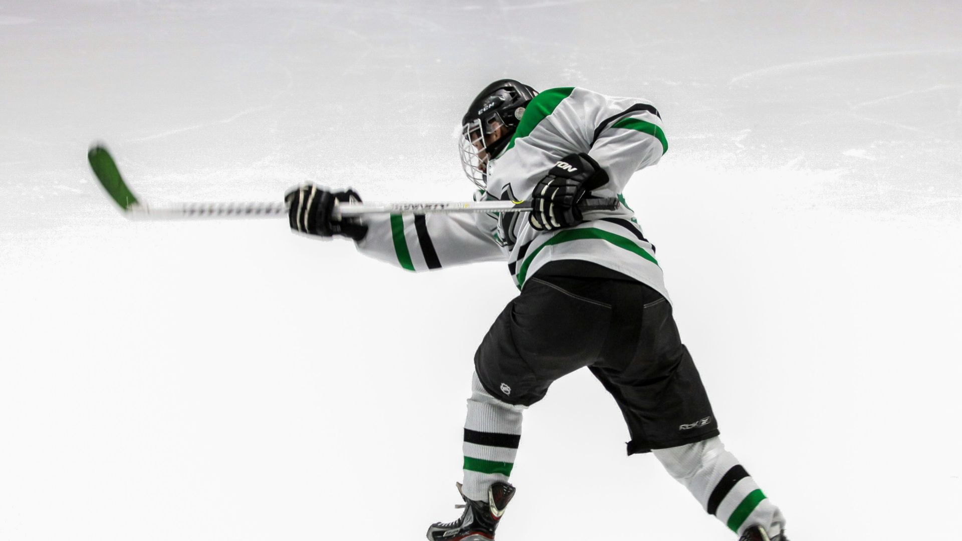 man wearing green and white ice hockey jersey while playing