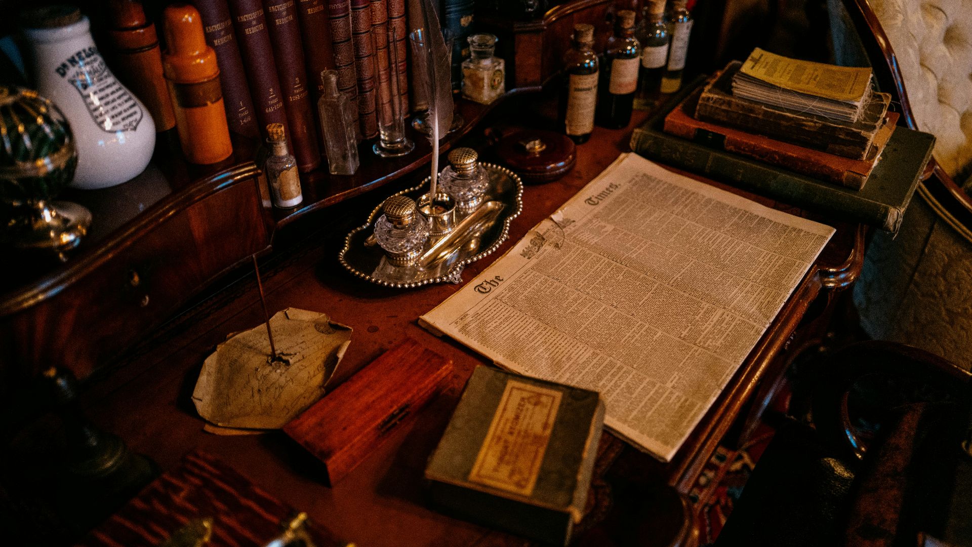 Old desk with books, inkwell, and papers.