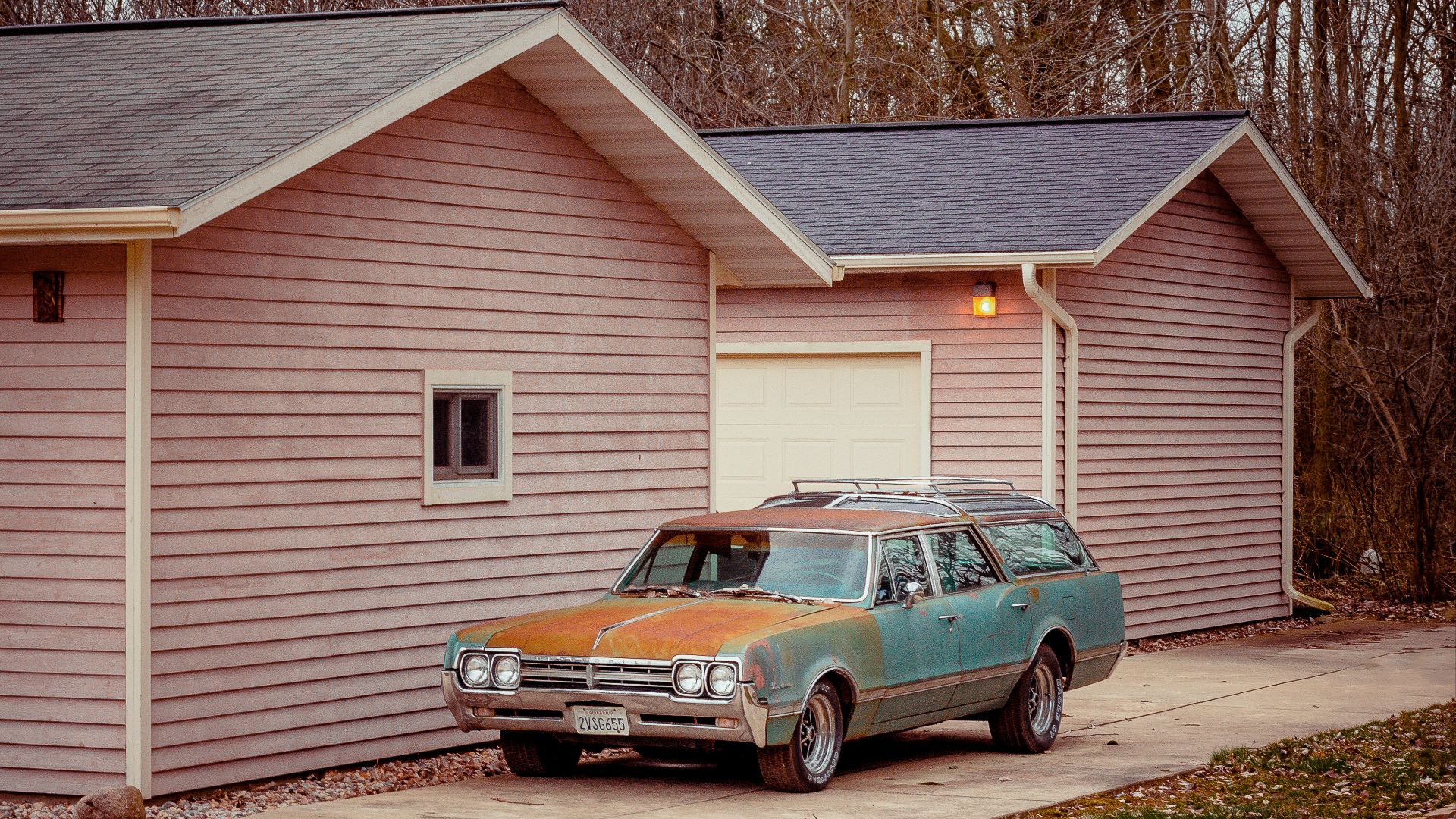 black sedan parked beside white wooden house