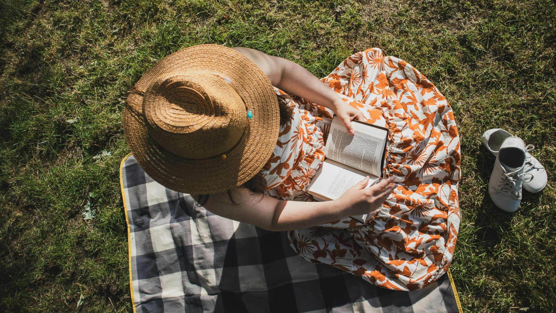 A woman sitting on a blanket on top of a field