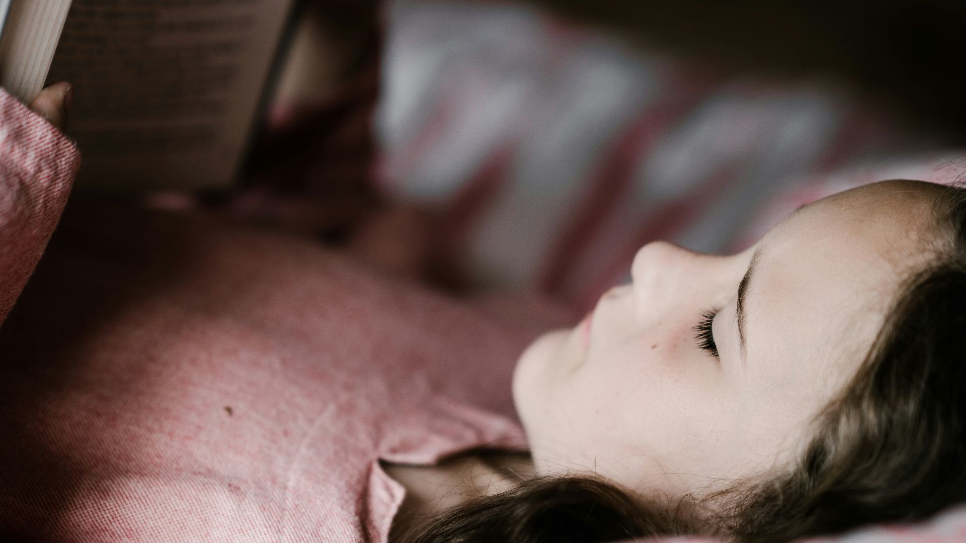 girl lying while reading book