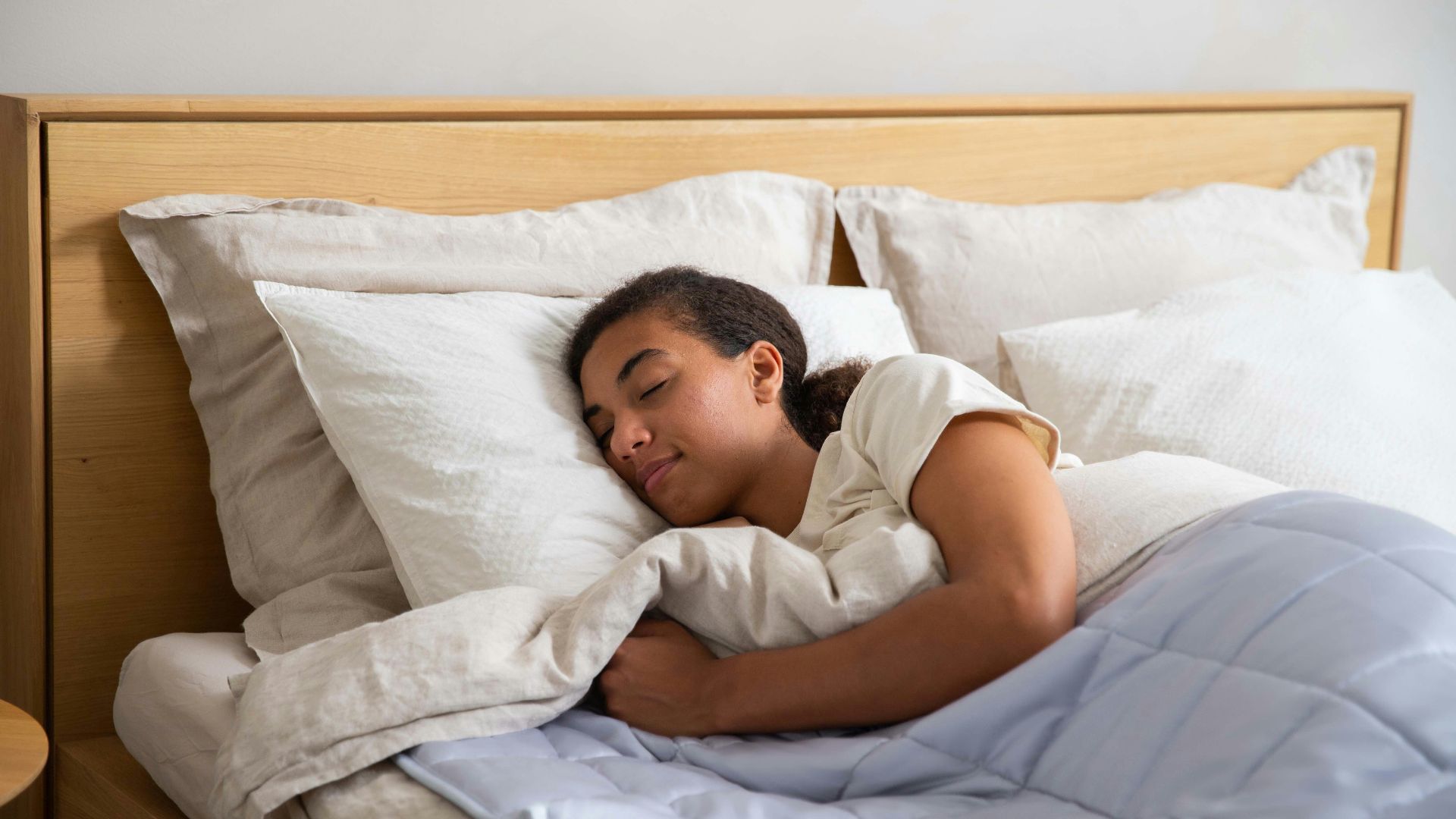 a young girl sleeping in a bed with white sheets