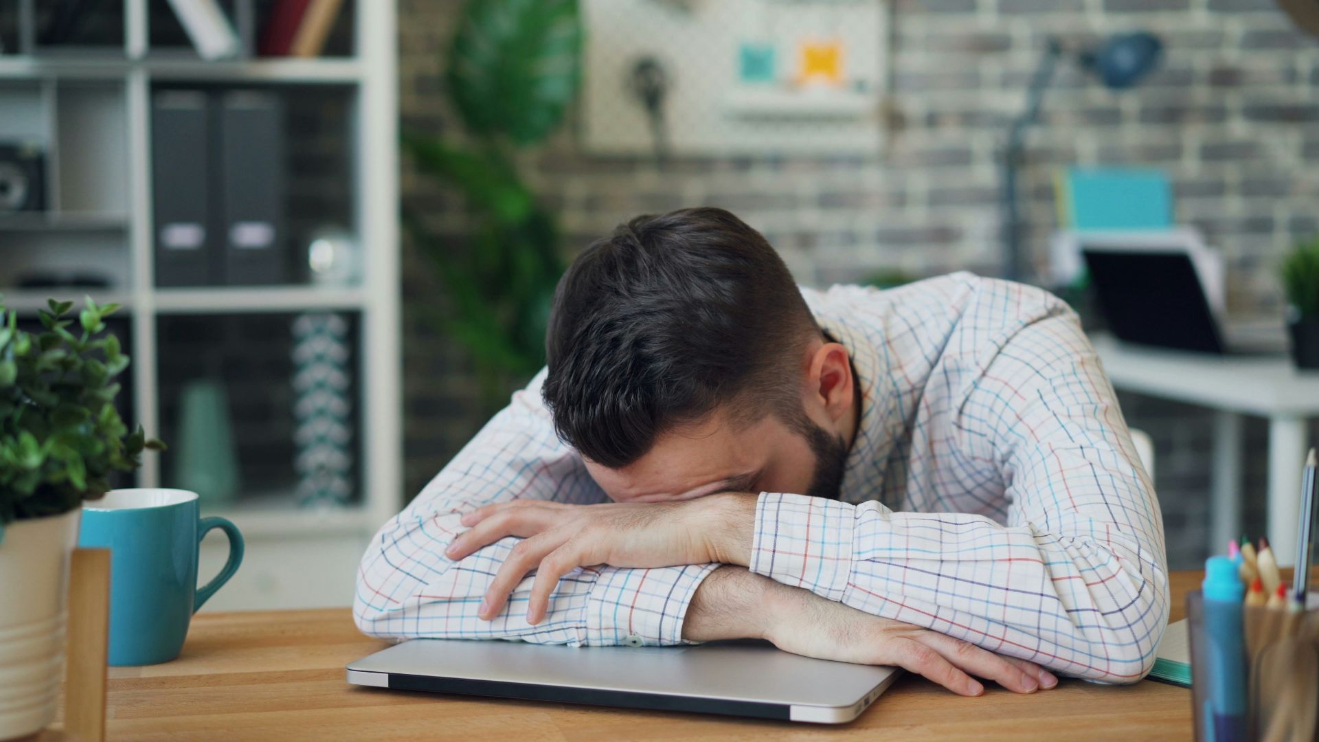 a man sitting at a desk with his head in his hands