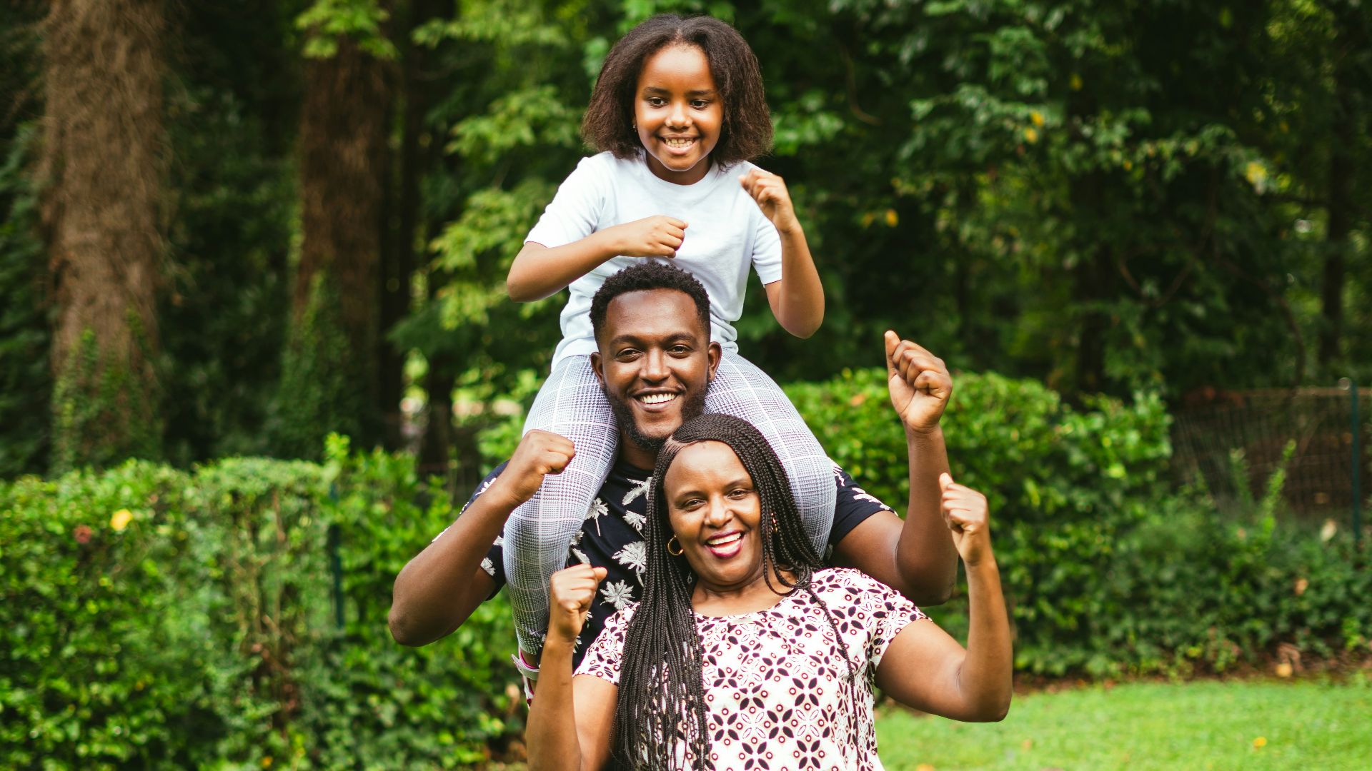 a man and two women holding a child on their shoulders