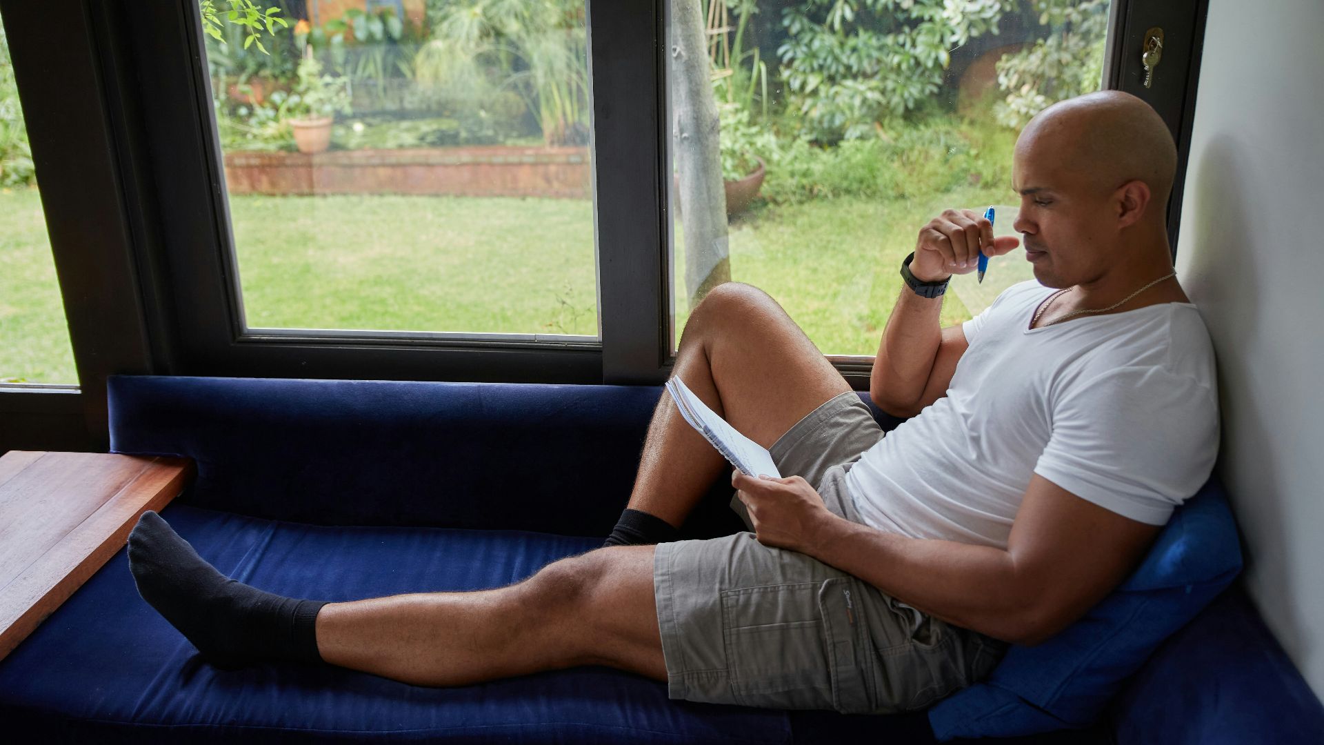 a man sitting on a blue couch looking out a window