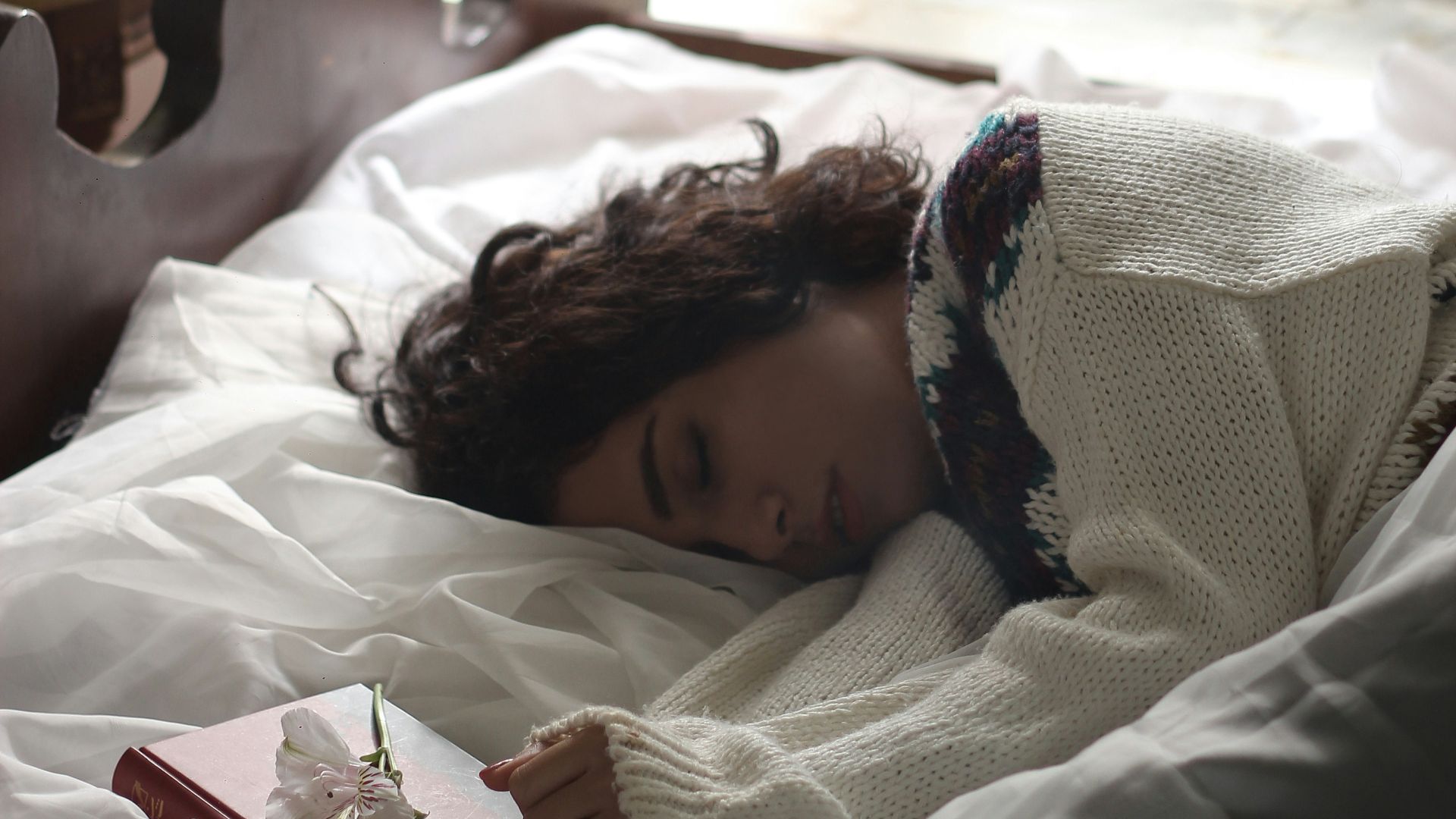 woman sleeping on bed beside book