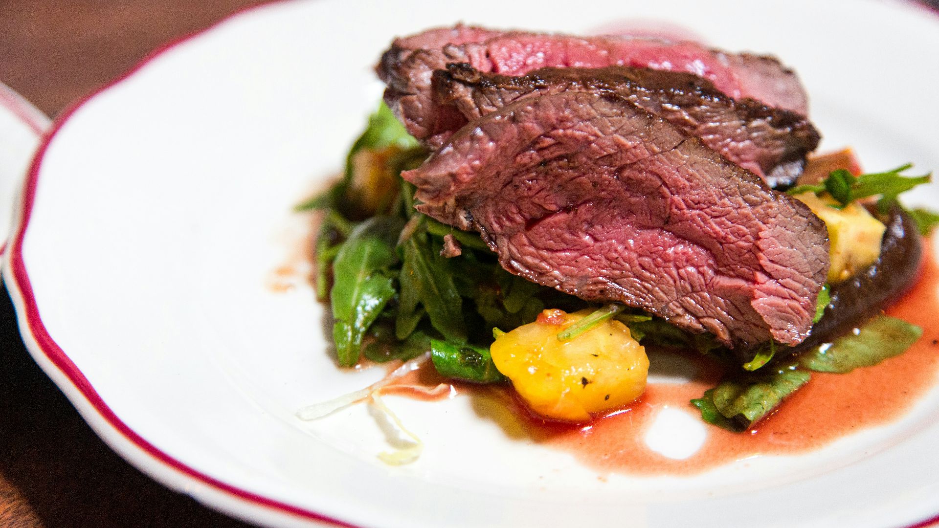 medium rare sliced steak in white ceramic plate