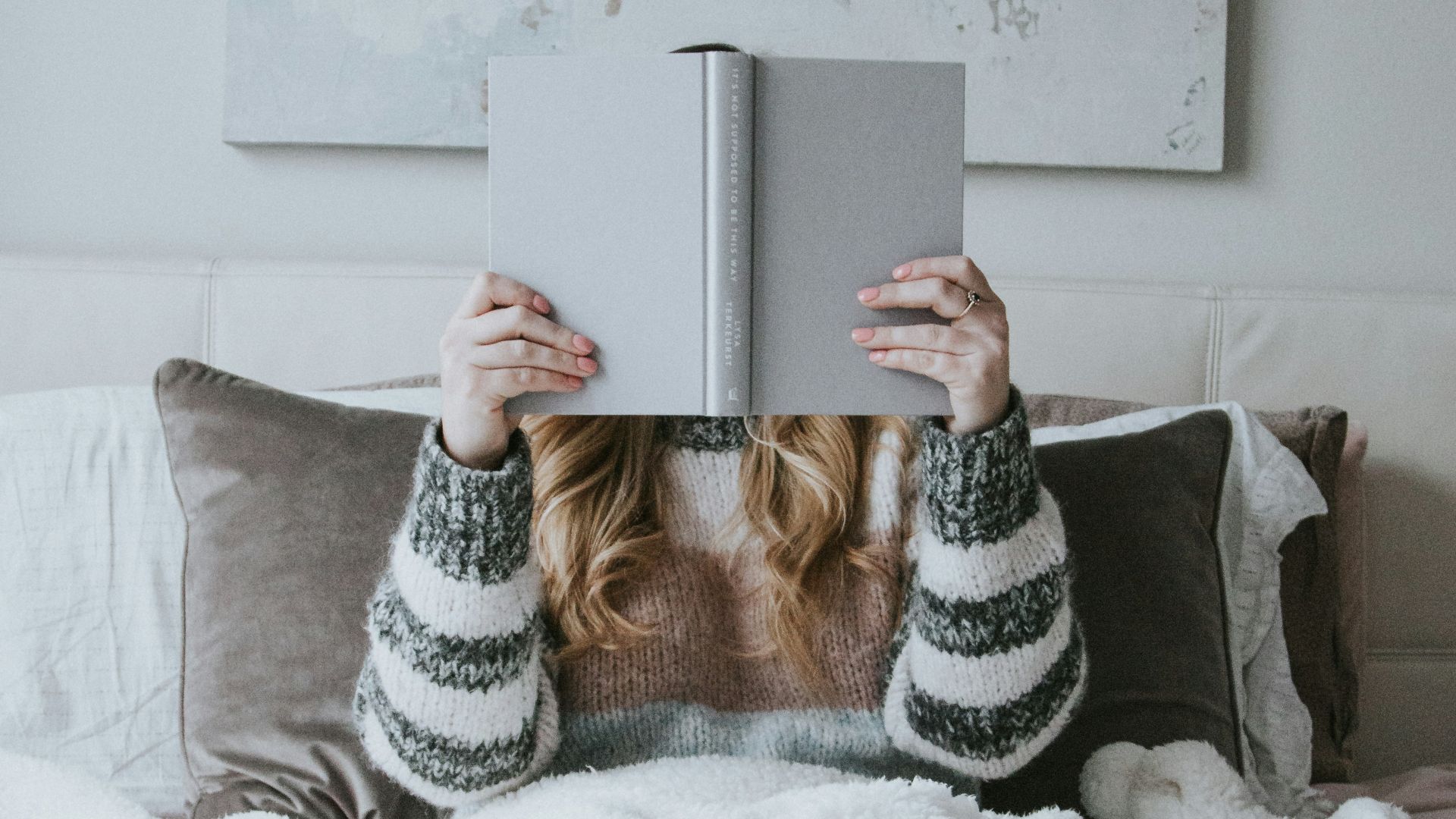 woman sitting on bed while holding book