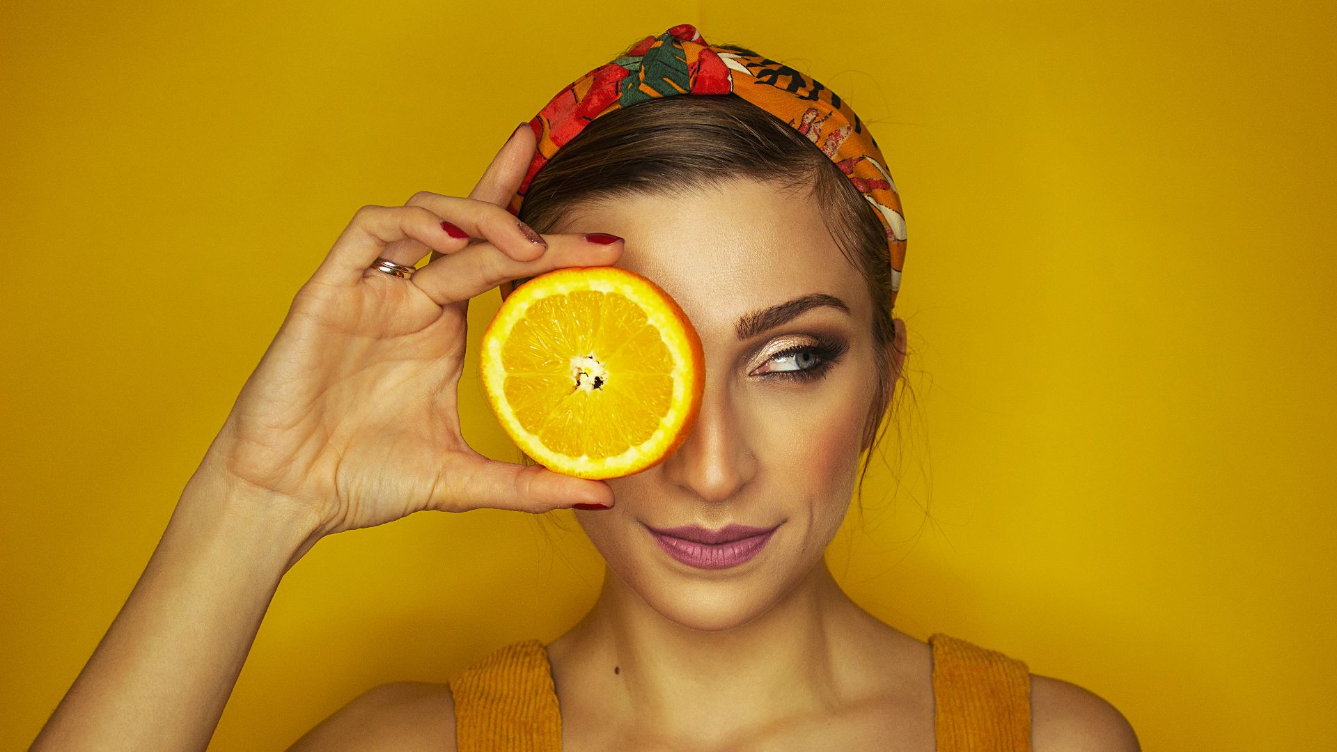 woman covering her right eye with orange slice