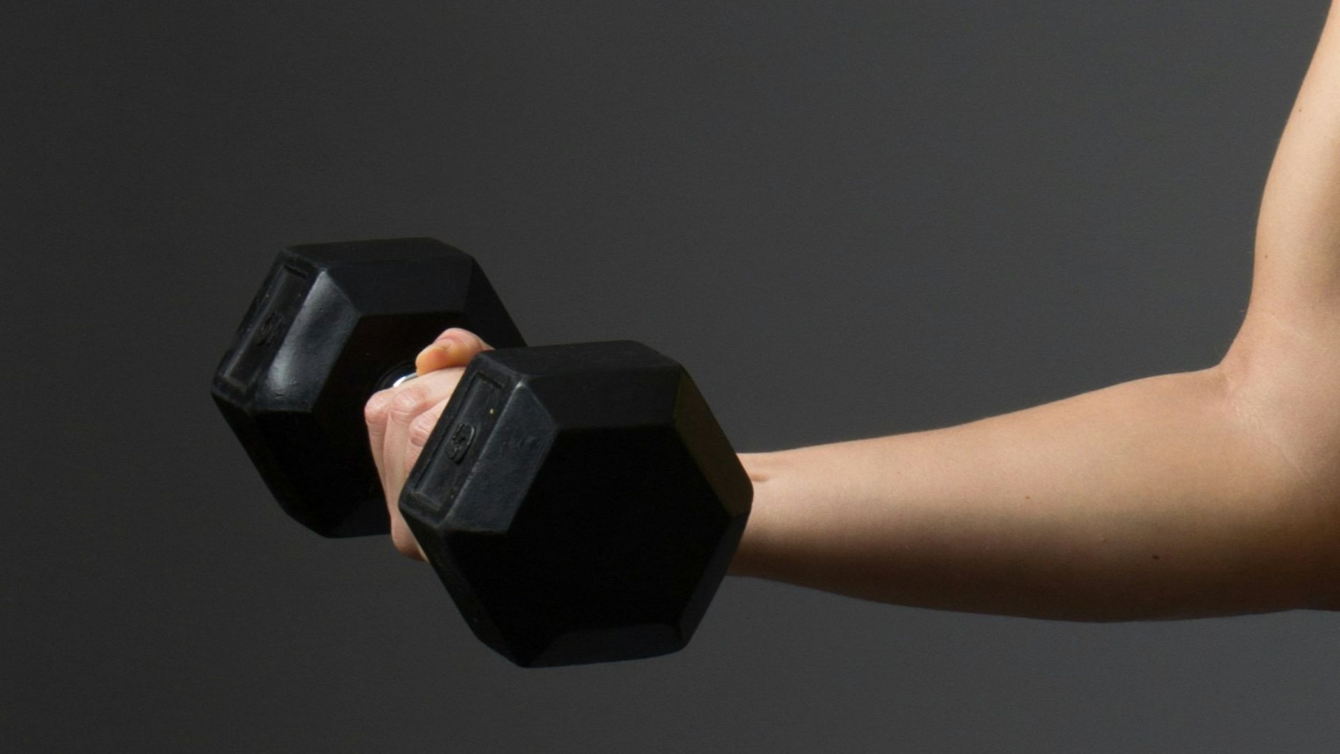 woman wearing pink sports bra holding dumbbells