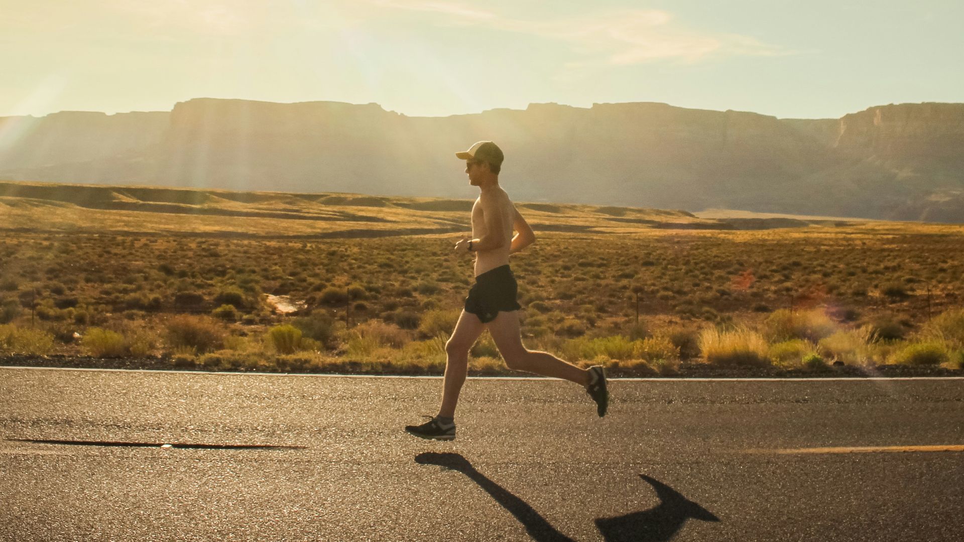 man in black shorts running on gray asphalt road during daytime