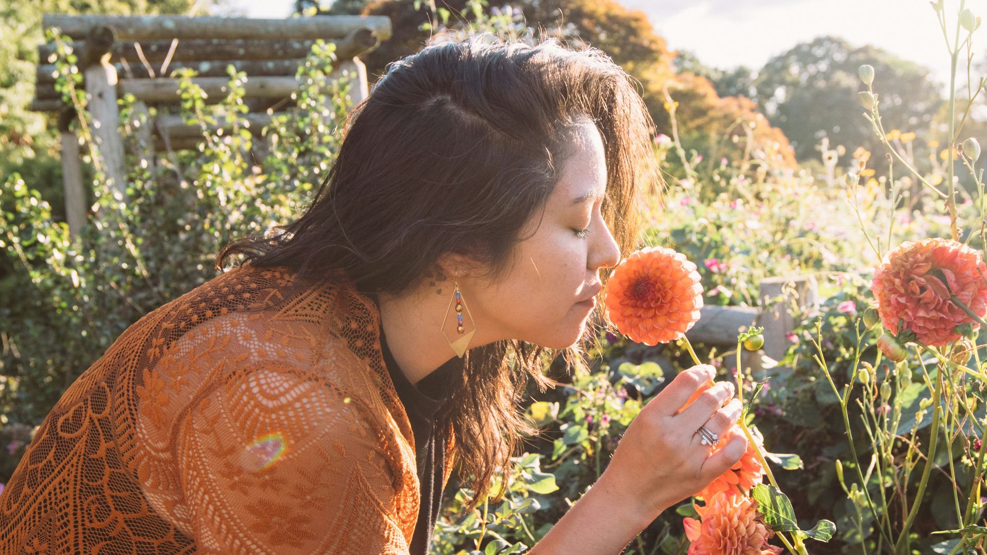 a woman smelling a flower in a garden