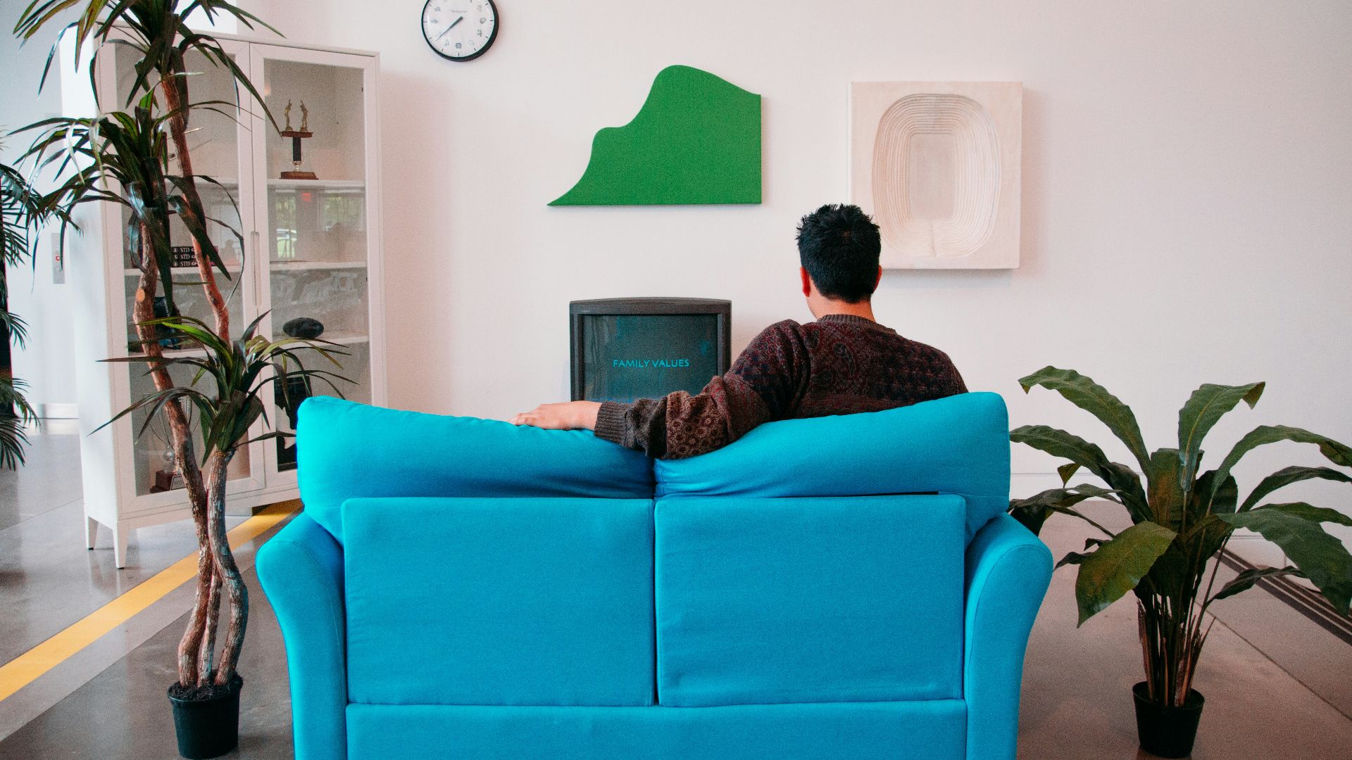 man in black and red jacket sitting on orange sofa