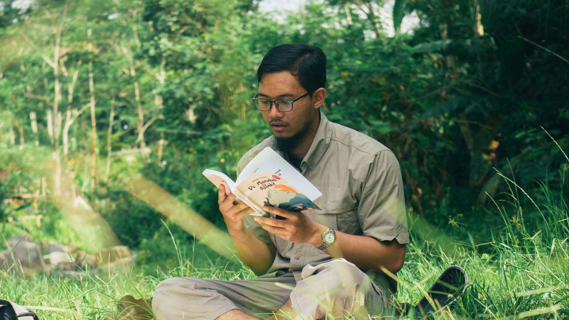 a man sitting in the grass reading a book