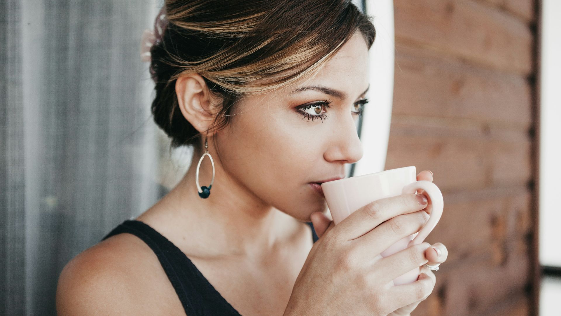 woman leaning on wall drinking coffee
