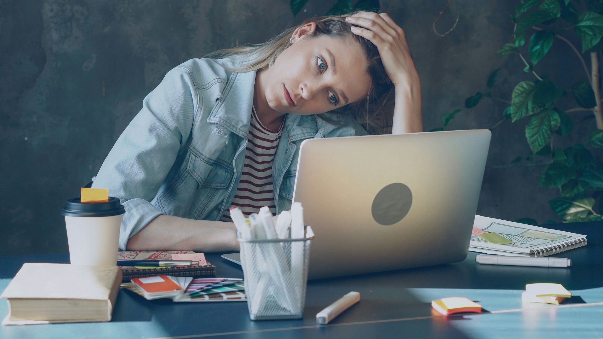 A woman appears stressed while working on laptop.