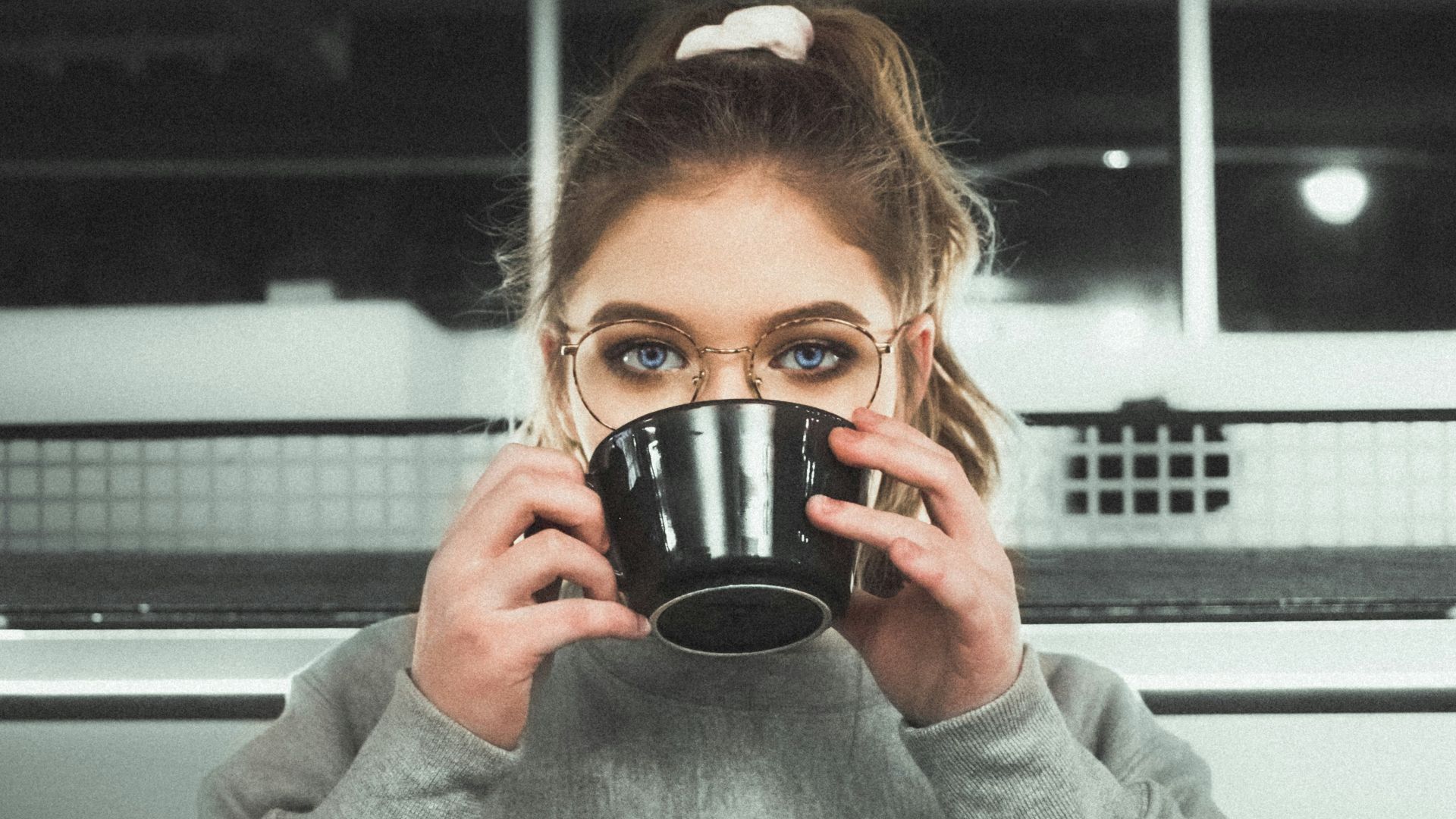 woman wearing glasses holding black ceramic mug