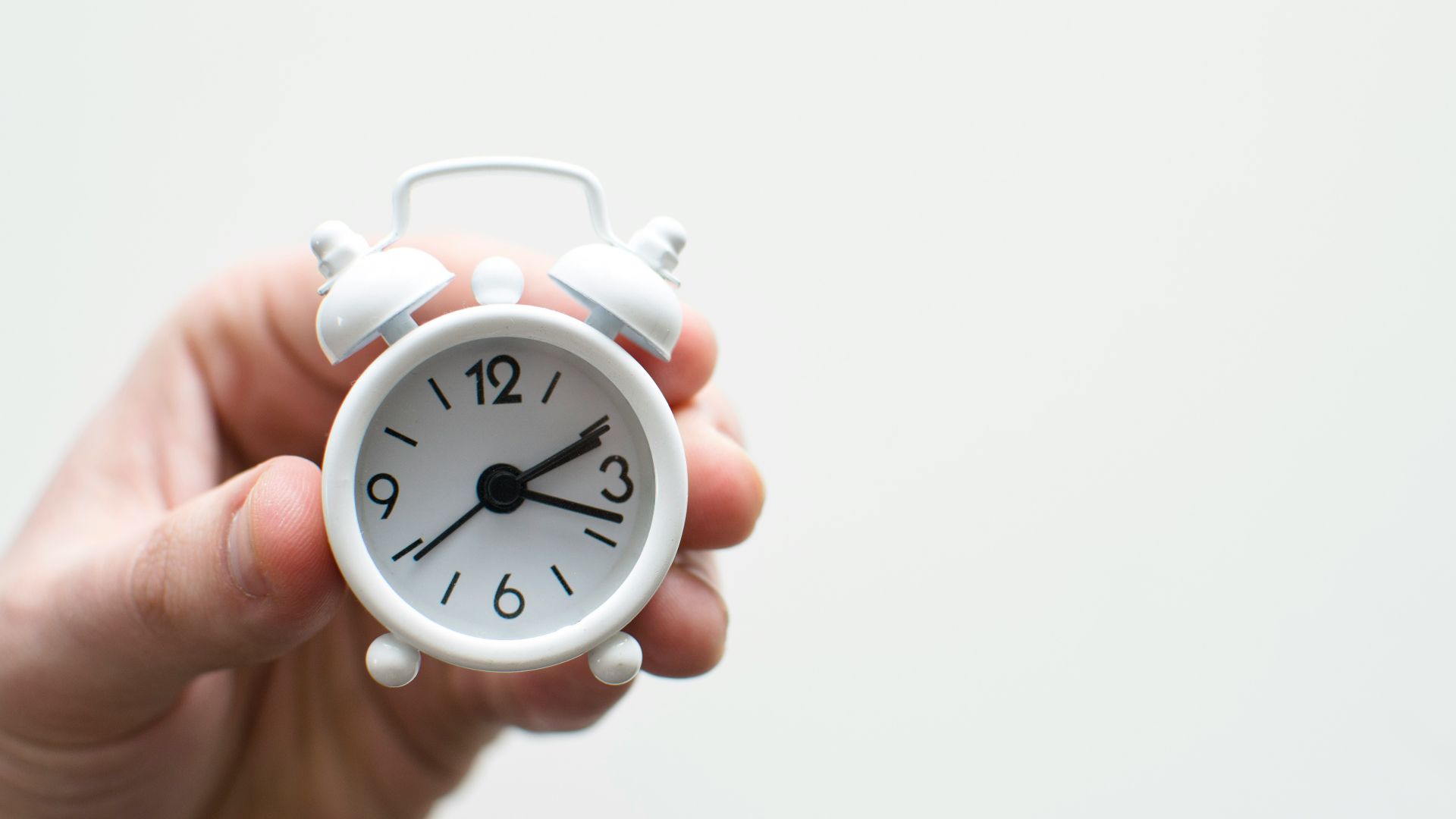person holding white mini bell alarmclock