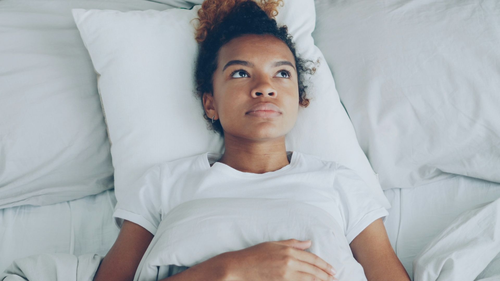 Young woman lying in bed with pillow.