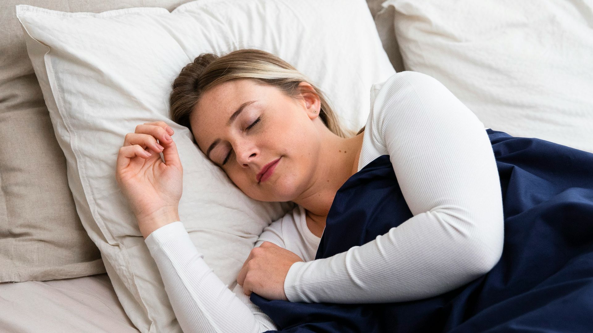 a woman sleeping on a bed with a blue blanket