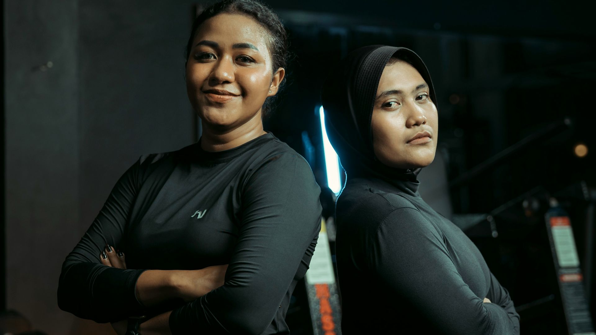 Two women stand together confidently in a gym.
