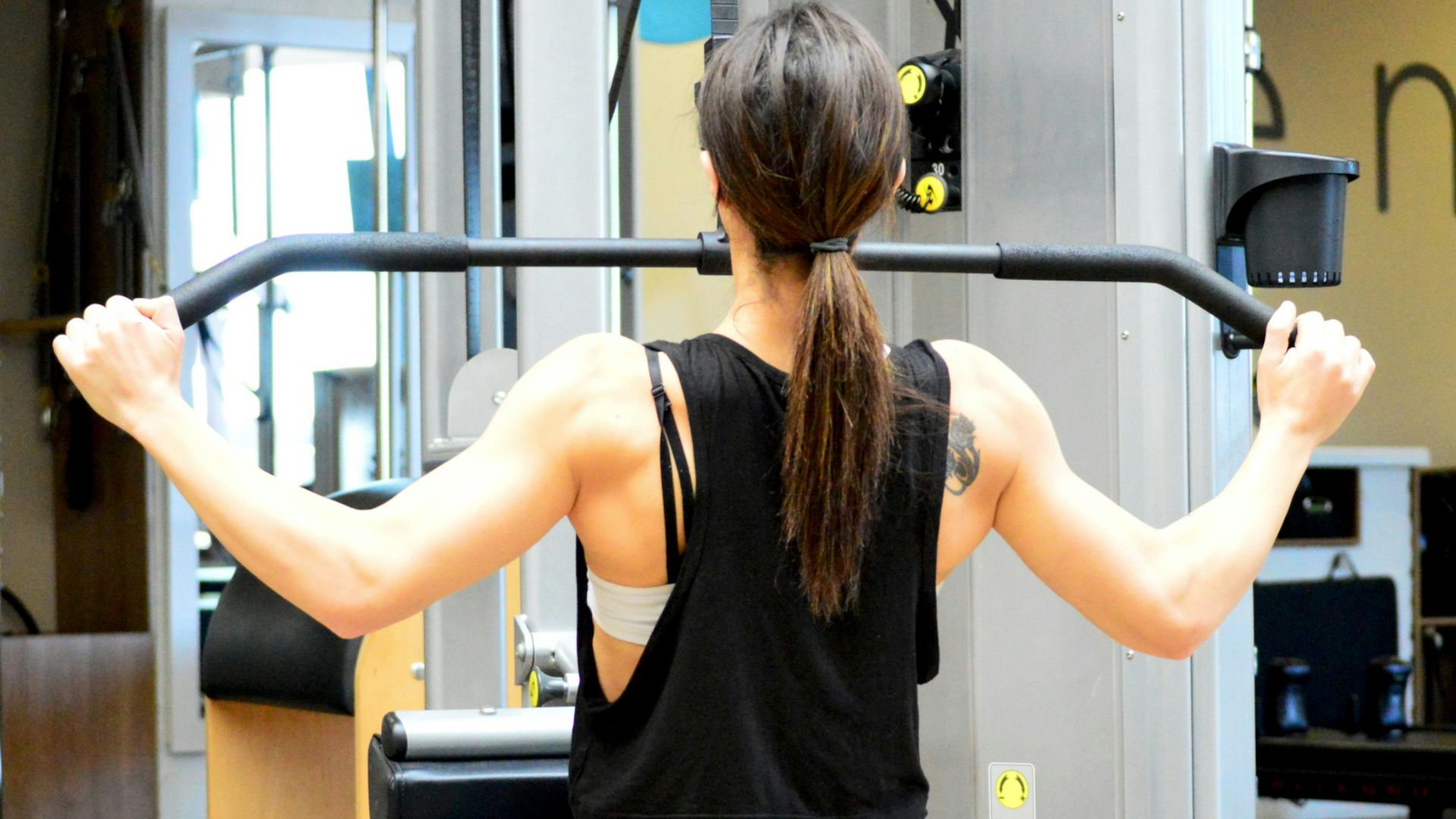 woman wearing black sleeveless top using gym equipment