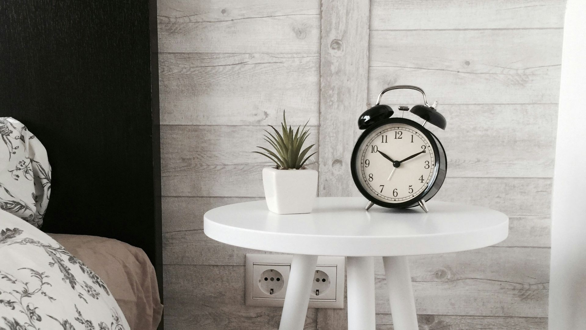 black alarm clock at 10:10 on white wooden table near table