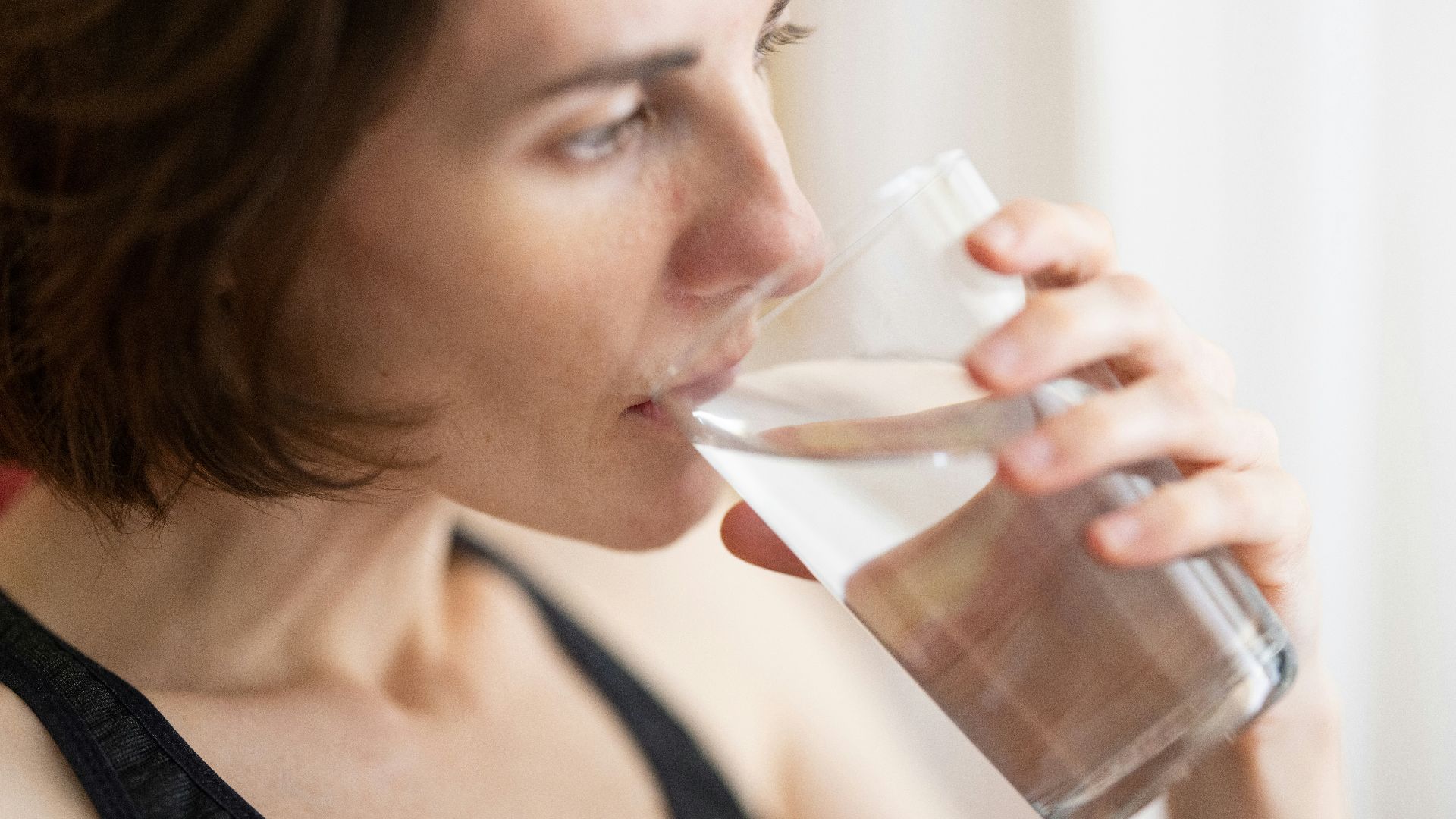 woman in black tank top drinking water