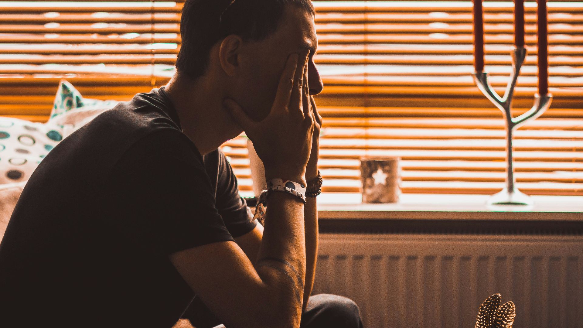man sitting on chair covering his eyes