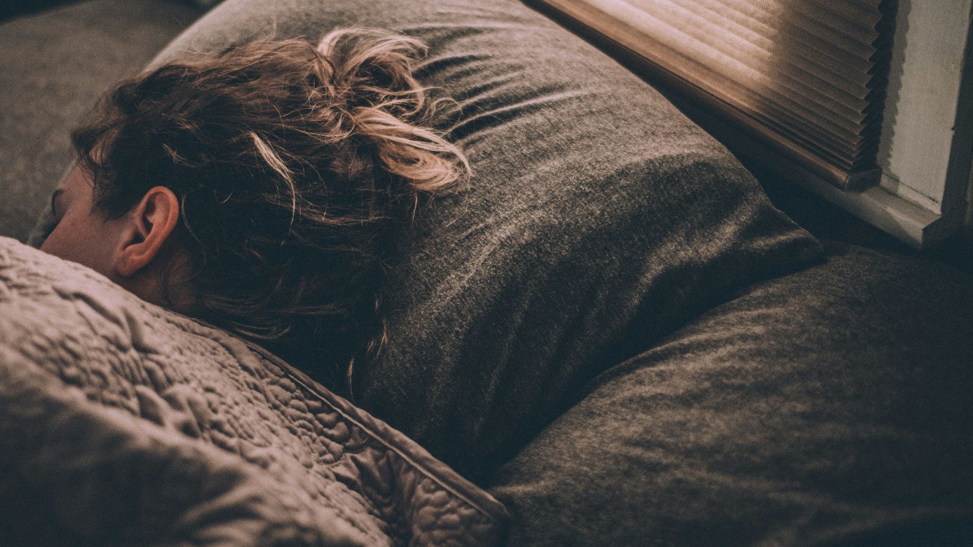 woman sleeping on bed under blankets