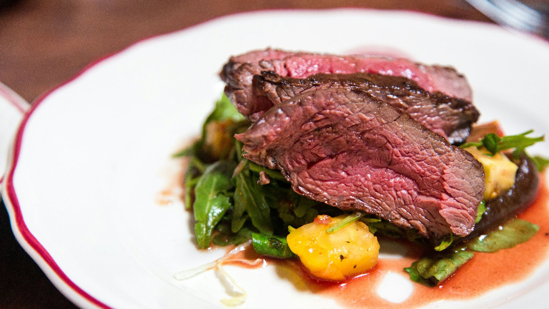 medium rare sliced steak in white ceramic plate