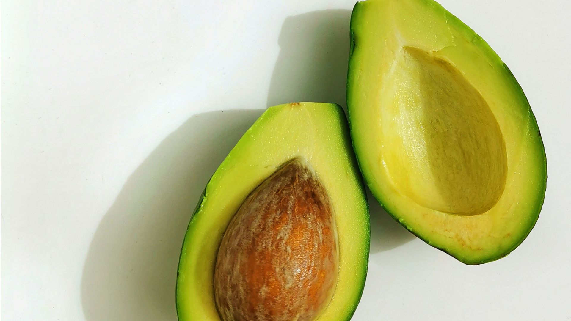 an avocado cut in half on a white surface